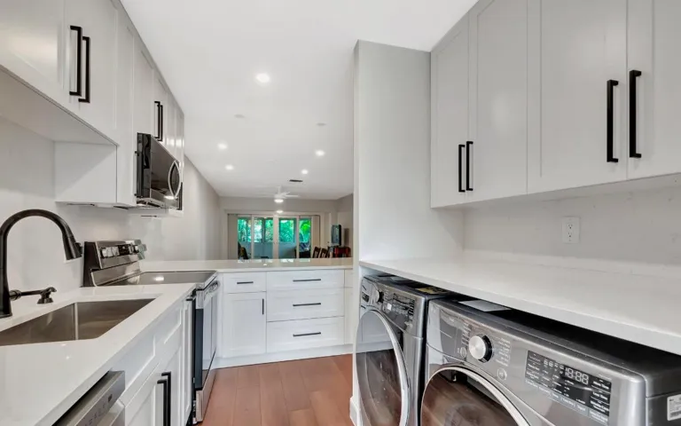 Modern kitchen featuring white cabinetry, stone countertops, stainless steel appliances, and wood-finish flooring