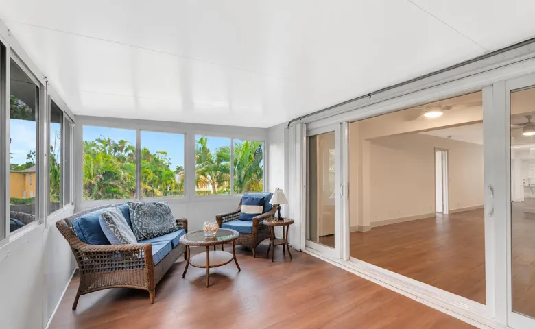 Enclosed sunroom featuring multiple large windows, wood-finish flooring, and sliding glass doors