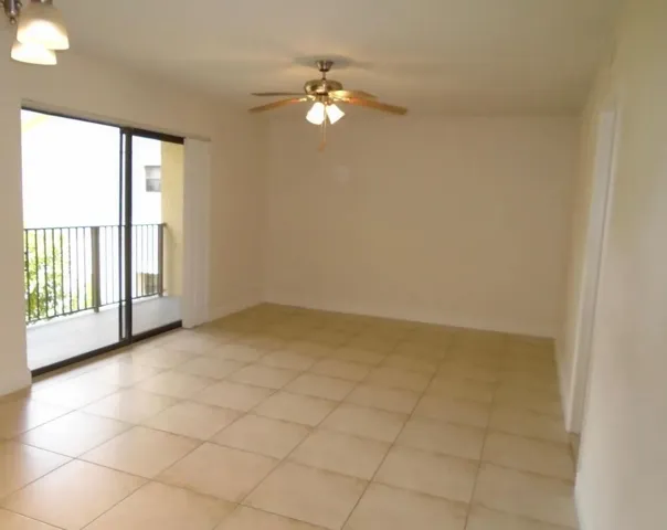 Tile flooring, sliding glass door, balcony with iron railings, ceiling fan with light fixture, and overhead lighting