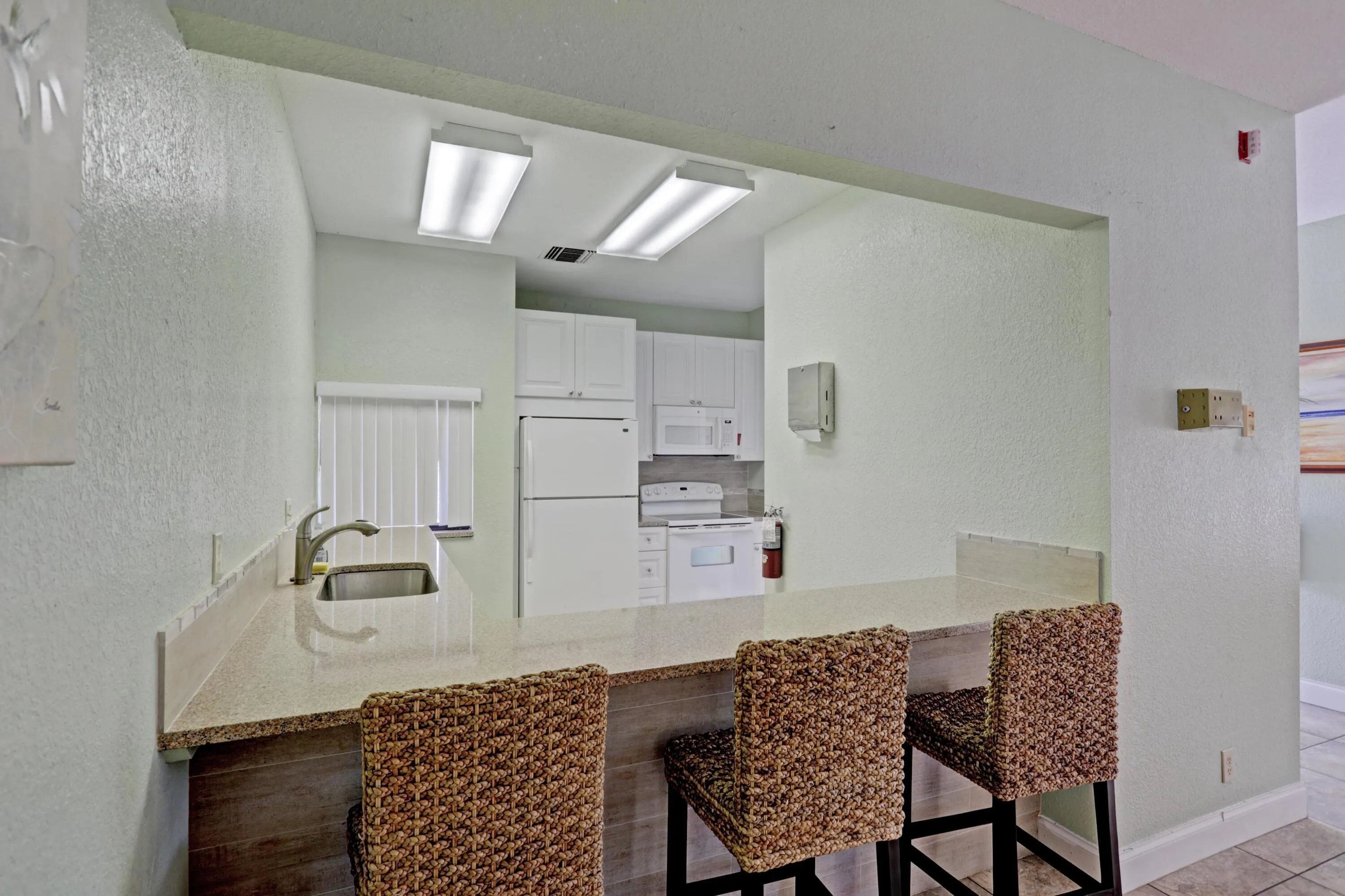 Kitchen pass-through featuring a granite-look countertop with an undermount sink and a gooseneck faucet