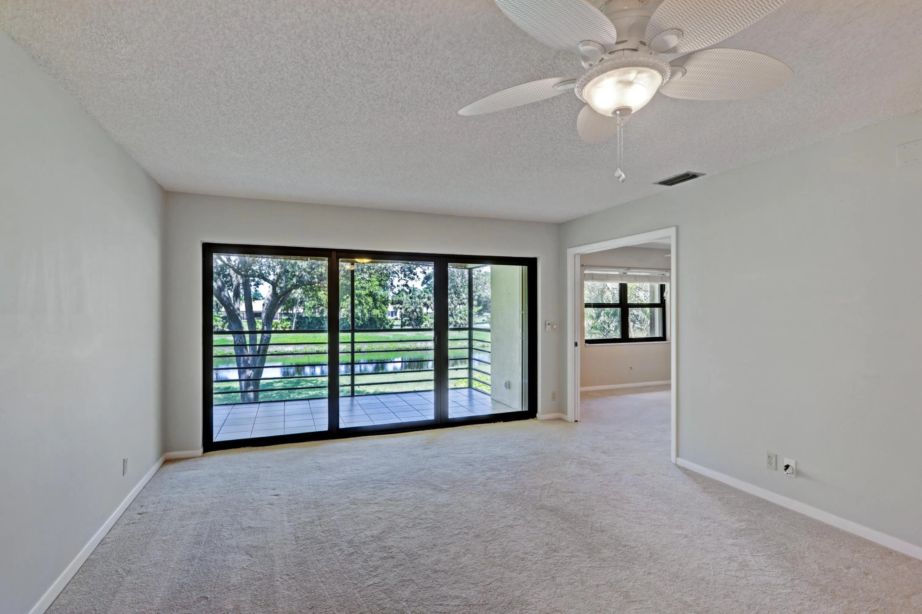 Spacious room featuring light-toned carpeting and a ceiling fan with integrated lighting