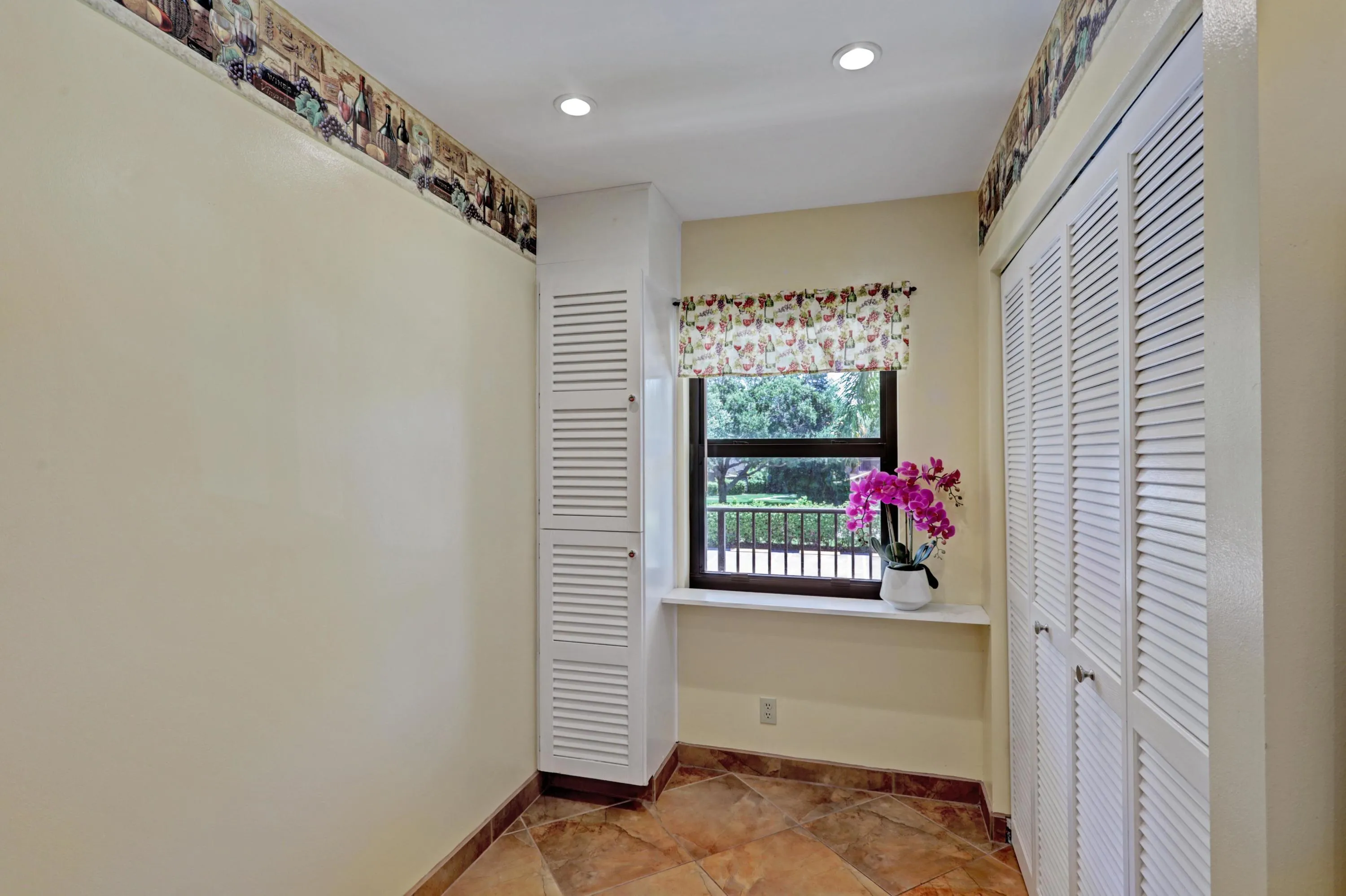 Window with outdoor views, white louvered doors, built-in shelving, recessed ceiling lighting, and tiled flooring