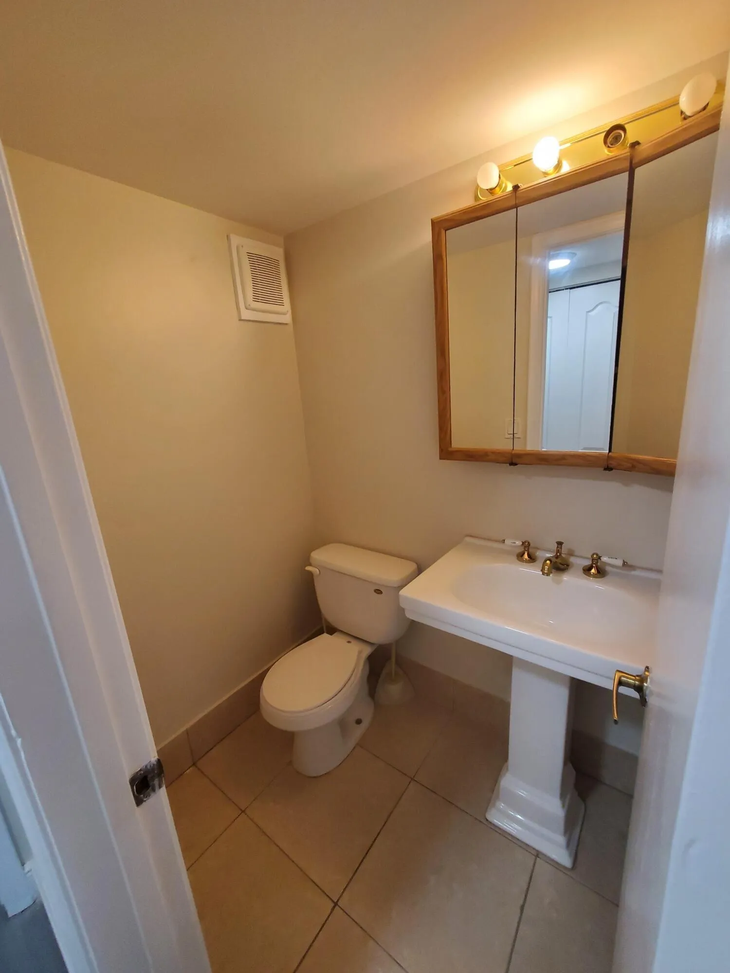 Updated Half Bath with Pedestal sink, ceramic tile flooring, and a mirrored medicine cabinet with wood-finish trim