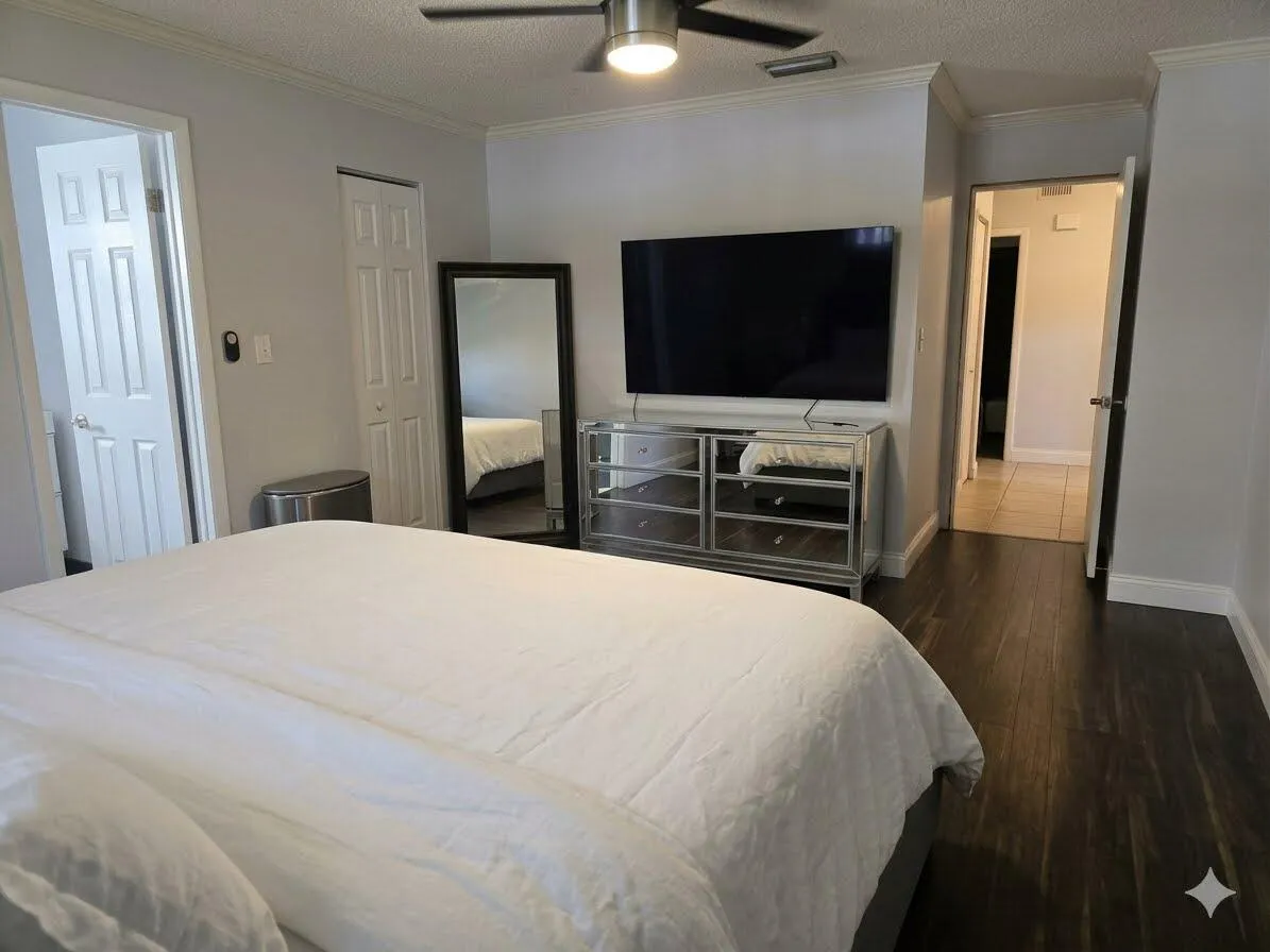 Dark wood-finish flooring with light gray walls, white crown molding, and a ceiling fan