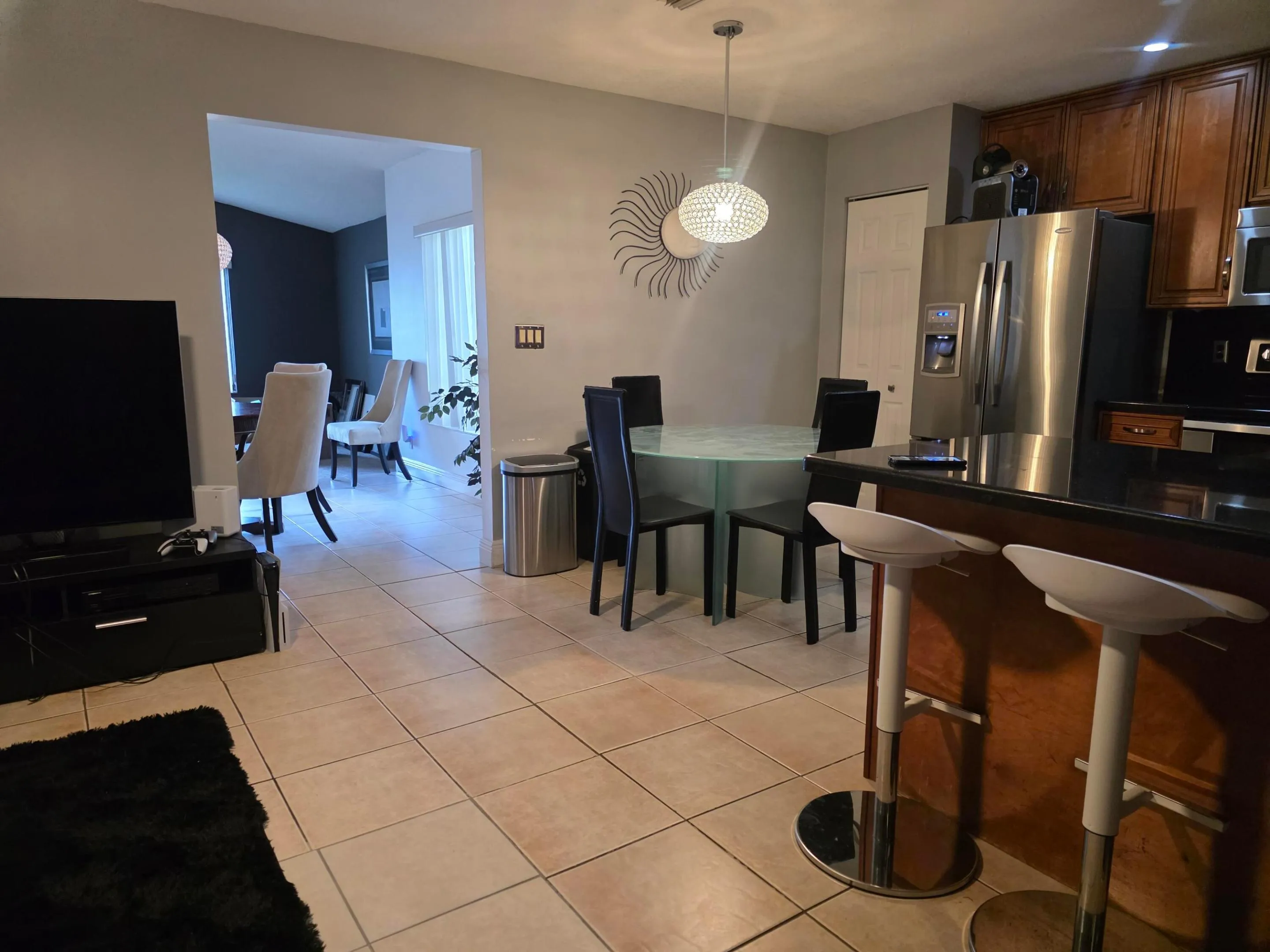 Tile flooring throughout, stainless steel appliances, dark wood cabinetry, breakfast bar, and an arched doorway