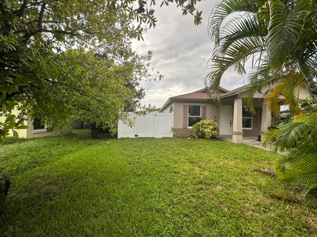 Single-story residence featuring a covered entry, exterior shutters, and a front yard with mature trees