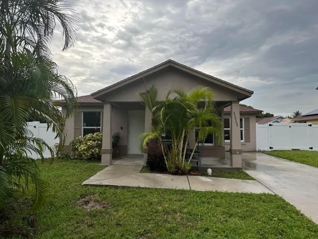 Single-story residence featuring a concrete driveway, covered entry, and a white privacy fence