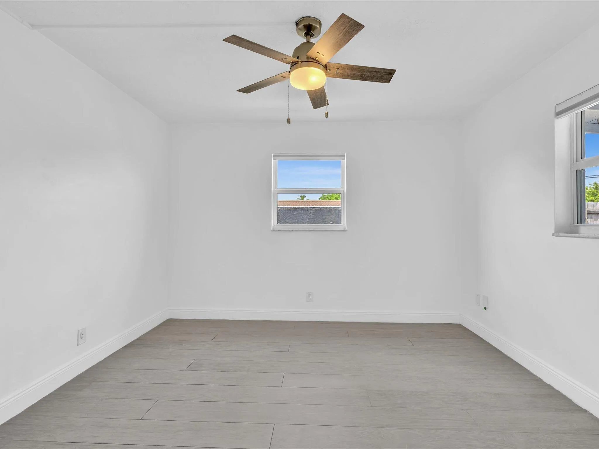 Bedroom with wood-finish ceiling fan with integrated lighting, and light grey vinyl flooring