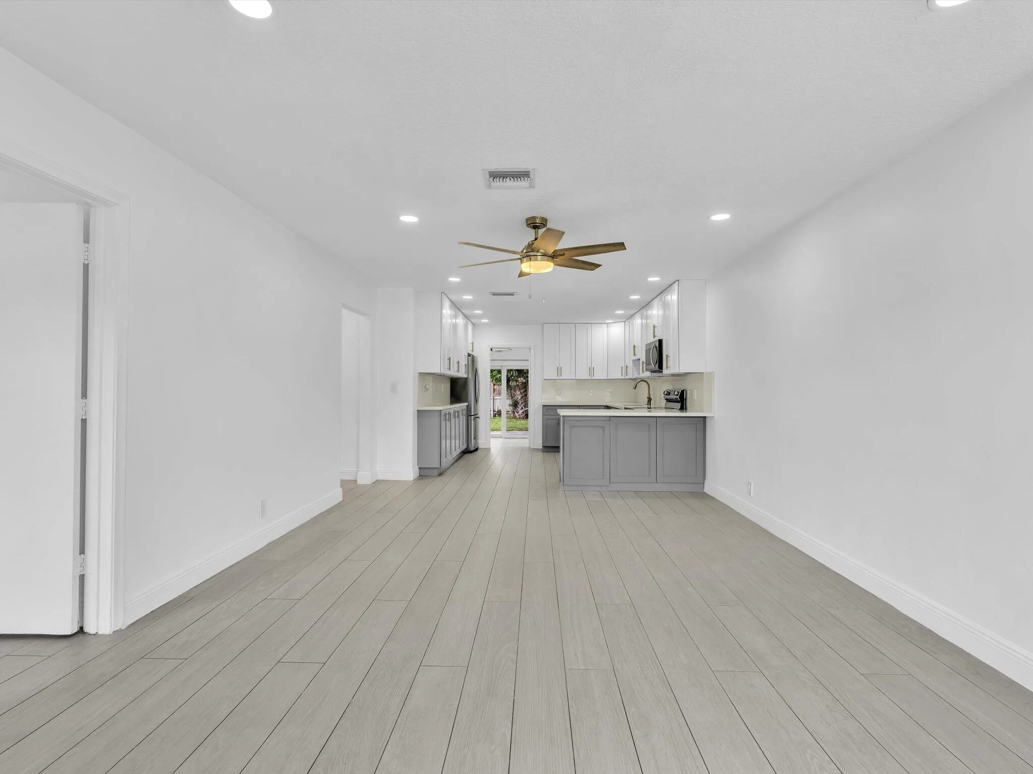 Open-concept layout with light wood-finish vinyl flooring, recessed lighting, and a ceiling fan