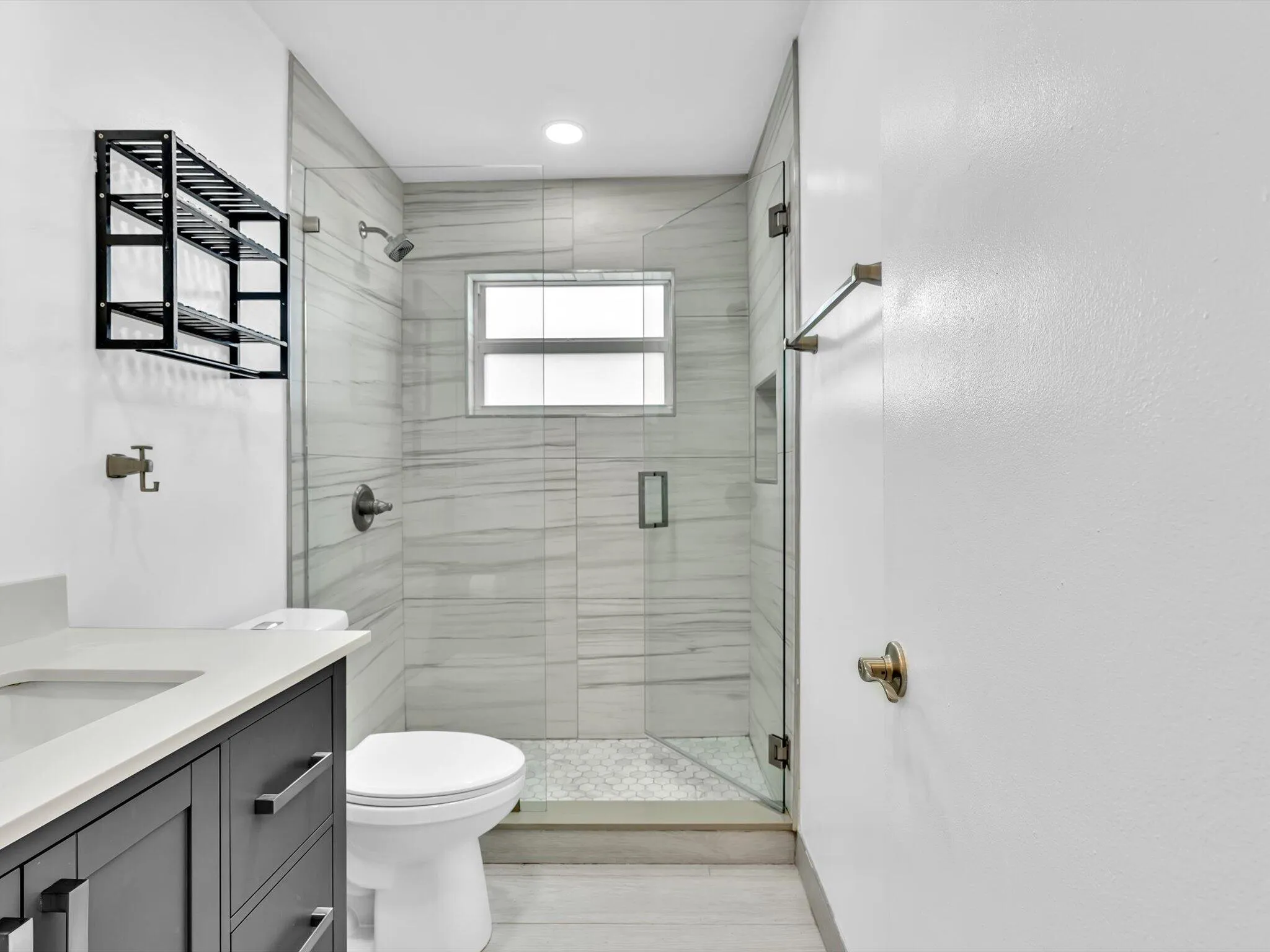 Walk-in shower with glass enclosure, tiled walls, and built-in niche
