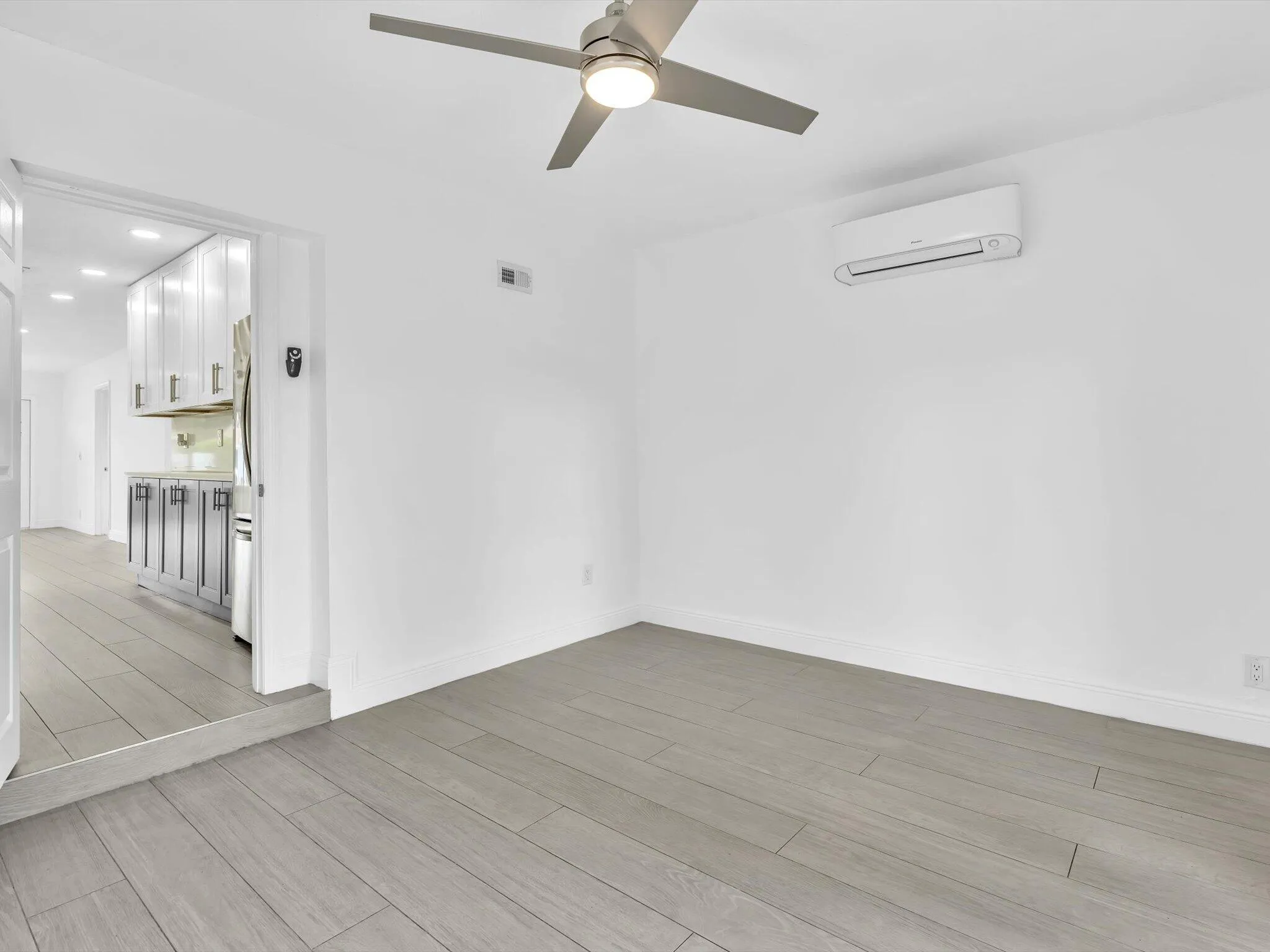 Bedroom with wood-finish ceiling fan with integrated lighting, and light grey vinyl flooring.