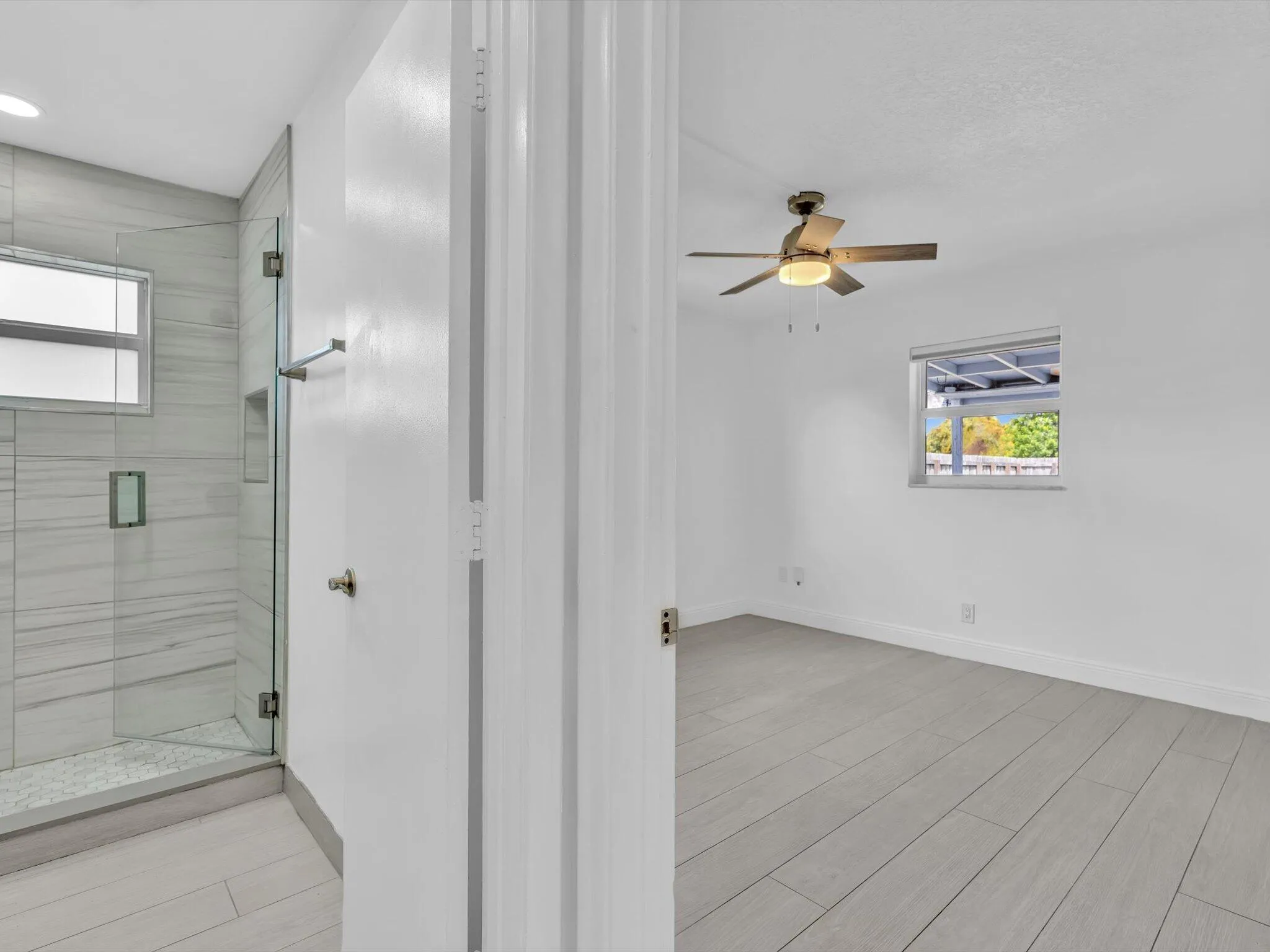View of bedroom and 2nd bathroom with glass-enclosed shower with horizontal tile surround and a built-in niche