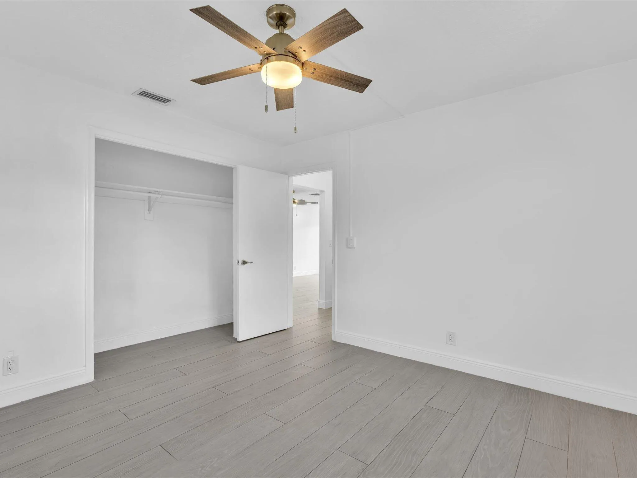 Bedroom with wood-finish ceiling fan with integrated lighting, and light grey vinyl flooring