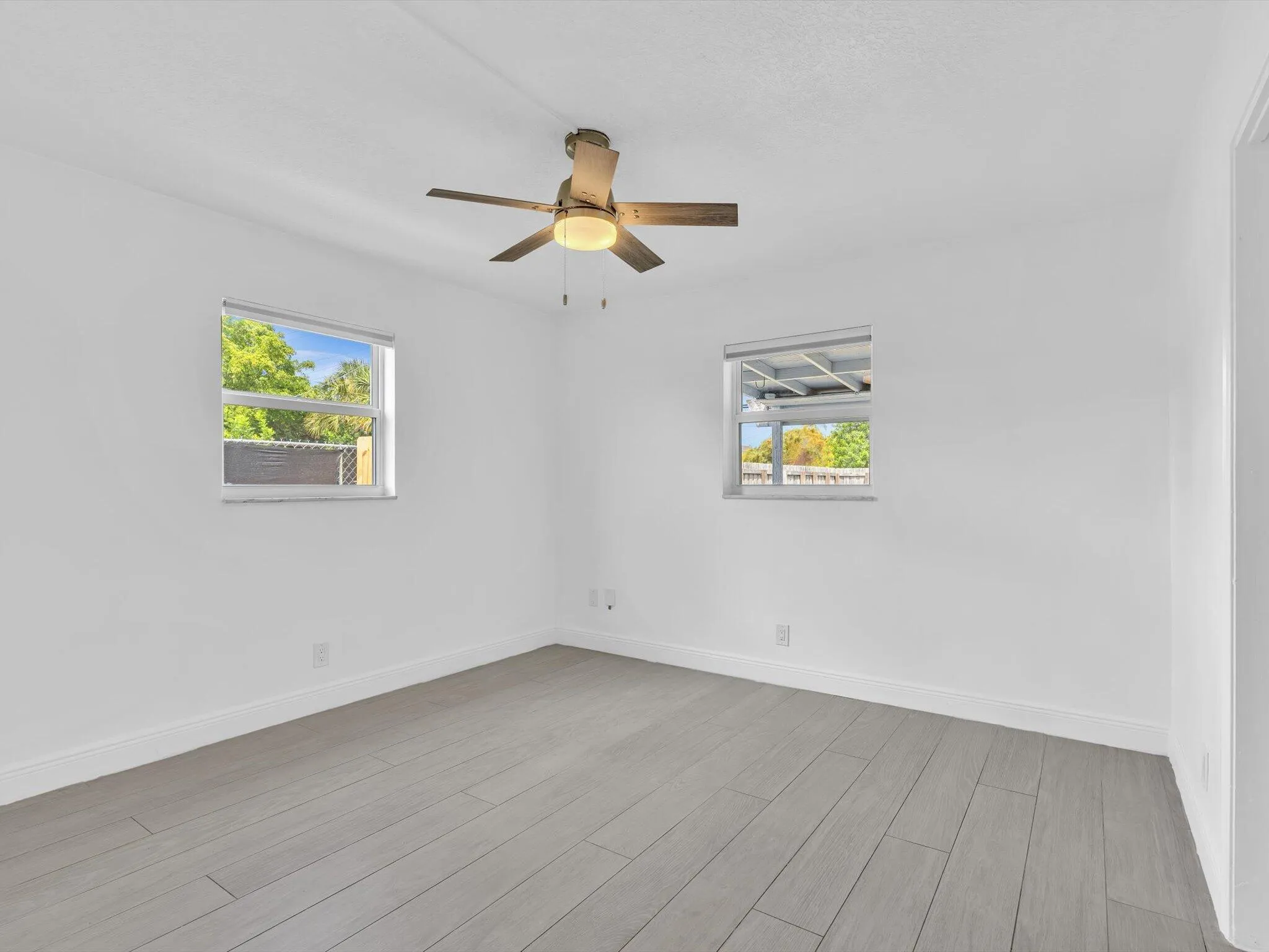 Bedroom with wood-finish ceiling fan with integrated lighting, and light grey vinyl flooring
