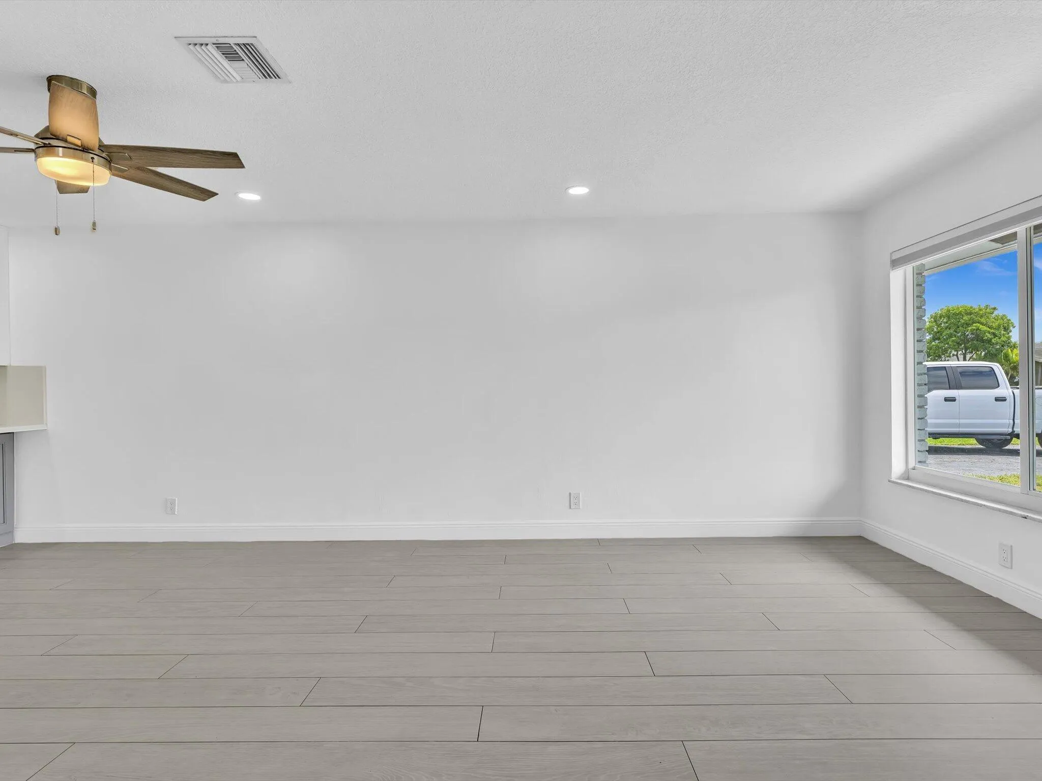 Spacious room featuring wood-finish vinyl flooring, recessed lighting, and a ceiling fan