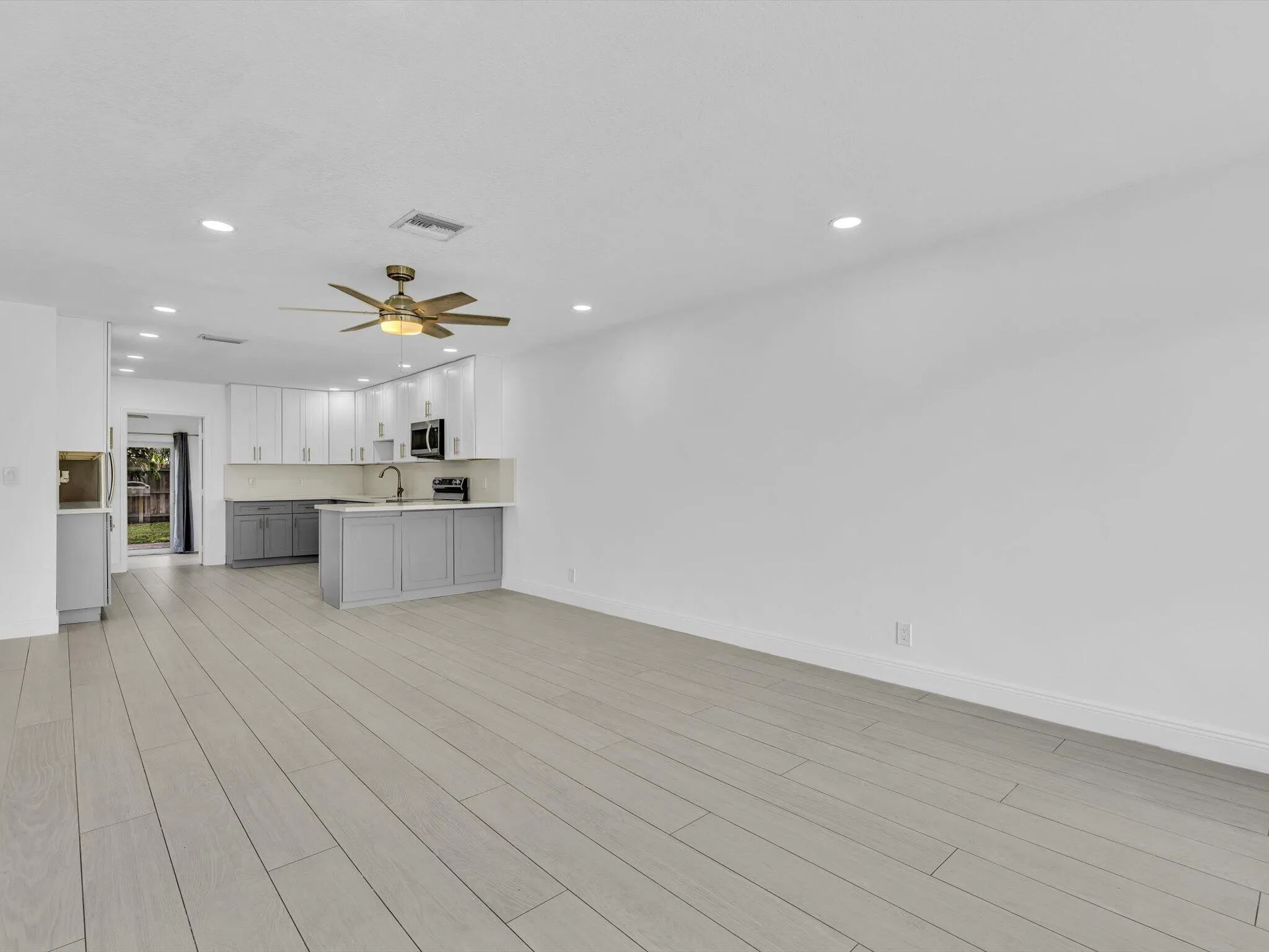 Open concept living space featuring wood-finish vinyl flooring, recessed lighting, and a ceiling fan