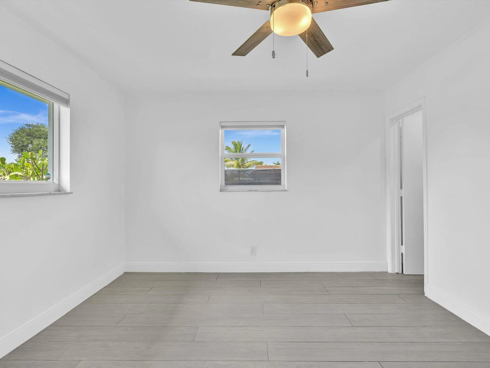 Bedroom with wood-finish ceiling fan with integrated lighting, and light grey vinyl flooring