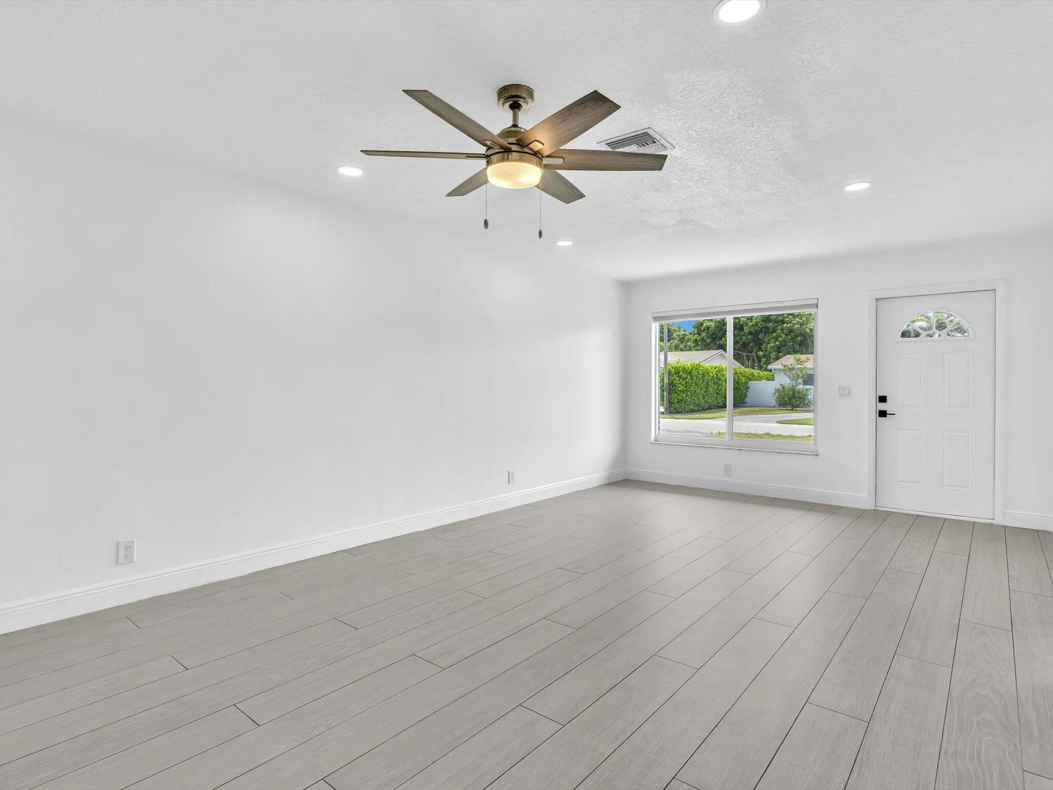 Spacious room featuring wood-finish vinyl flooring, recessed lighting, and a ceiling fan