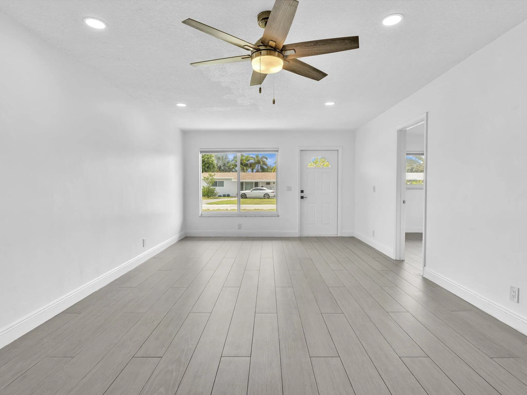 Spacious room featuring wood-finish vinyl flooring, recessed lighting, and a ceiling fan