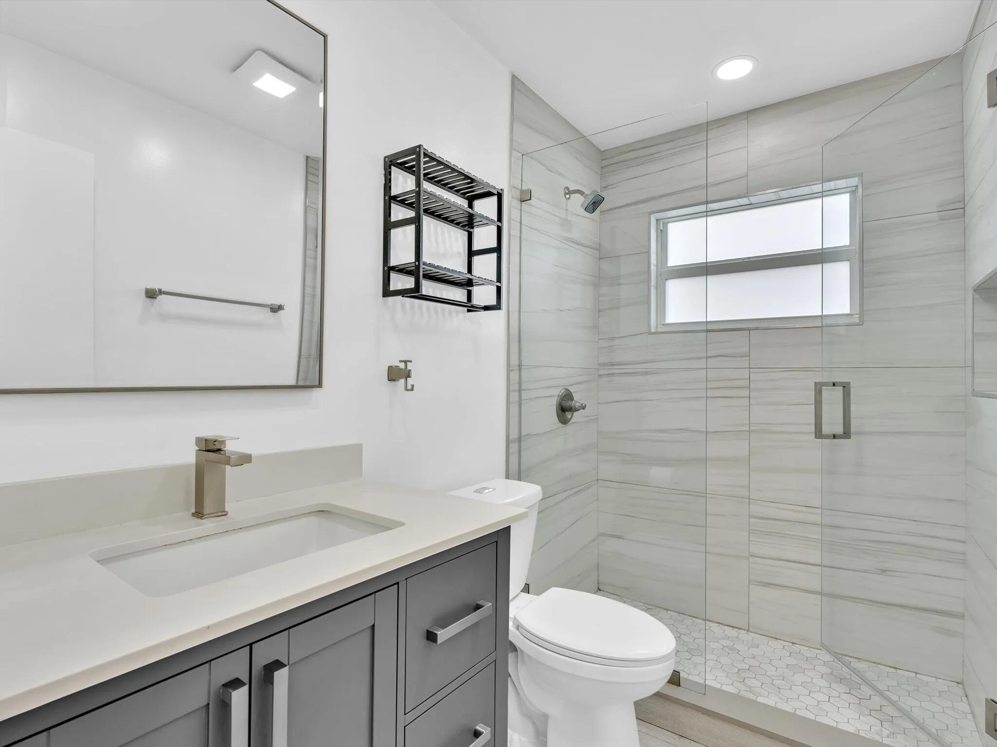 Walk-in shower with glass enclosure, tiled walls, and built-in niche
