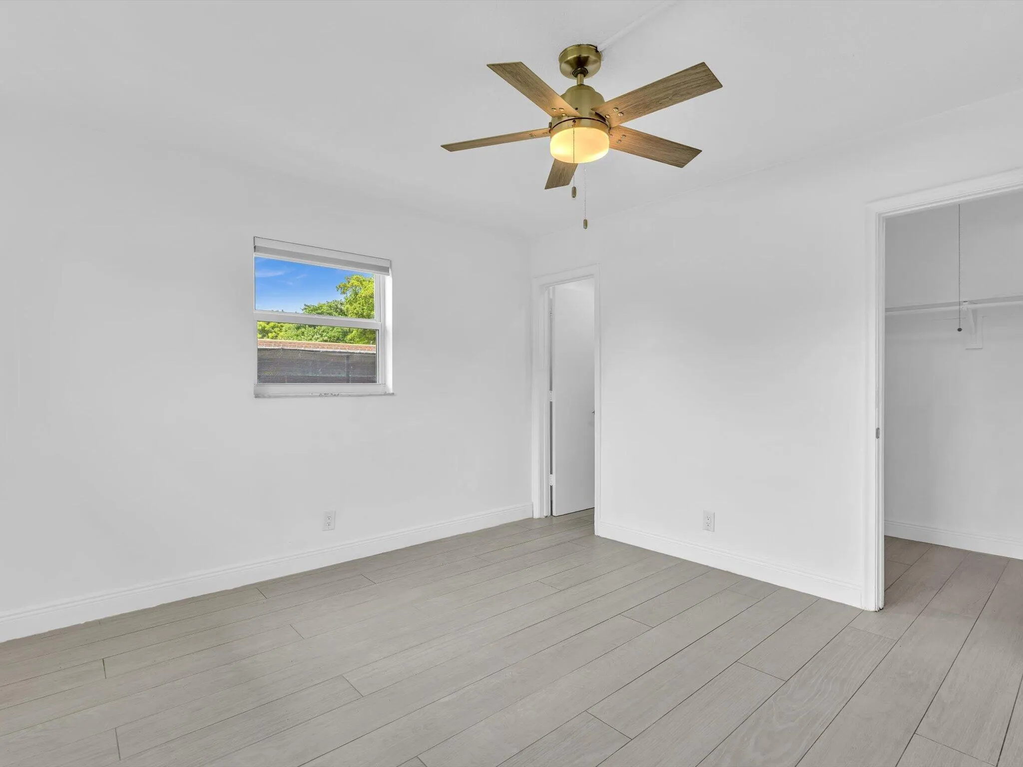Bedroom with wood-finish ceiling fan with integrated lighting, and light grey vinyl flooring