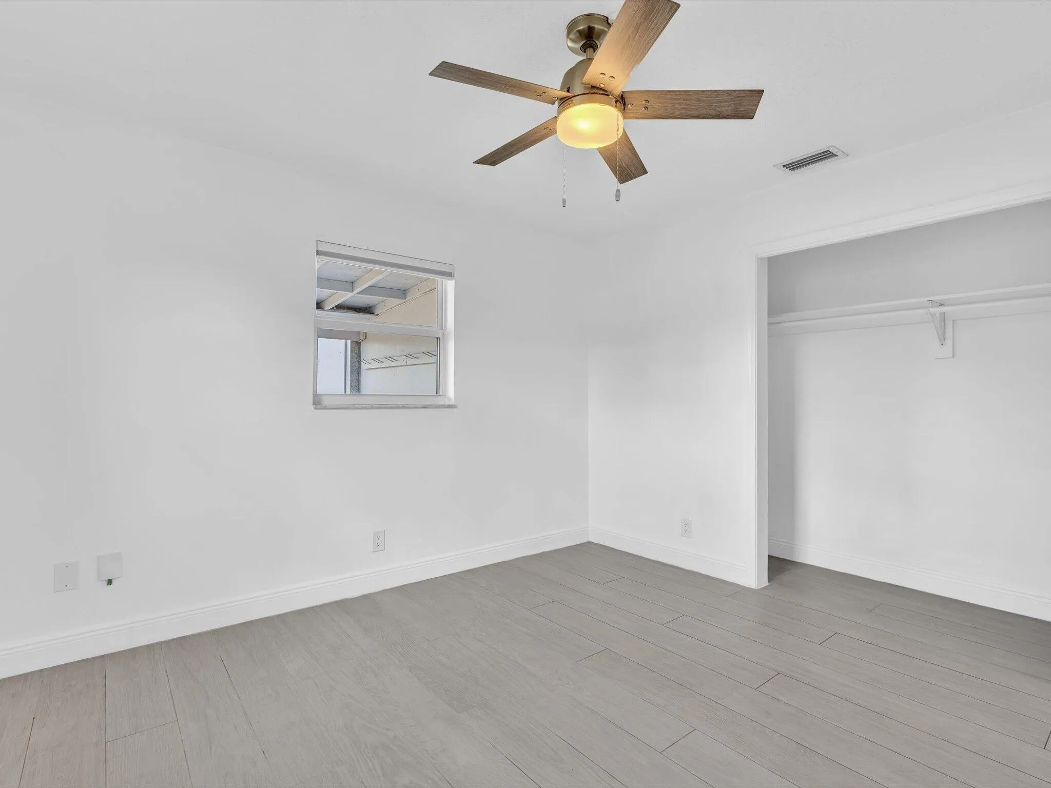 Bedroom with wood-finish ceiling fan with integrated lighting, and light grey vinyl flooring