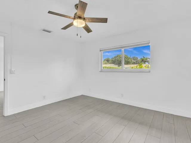 Bedroom with wood-finish ceiling fan with integrated lighting, and light grey vinyl flooring