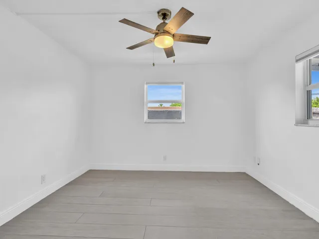 Bedroom with wood-finish ceiling fan with integrated lighting, and light grey vinyl flooring