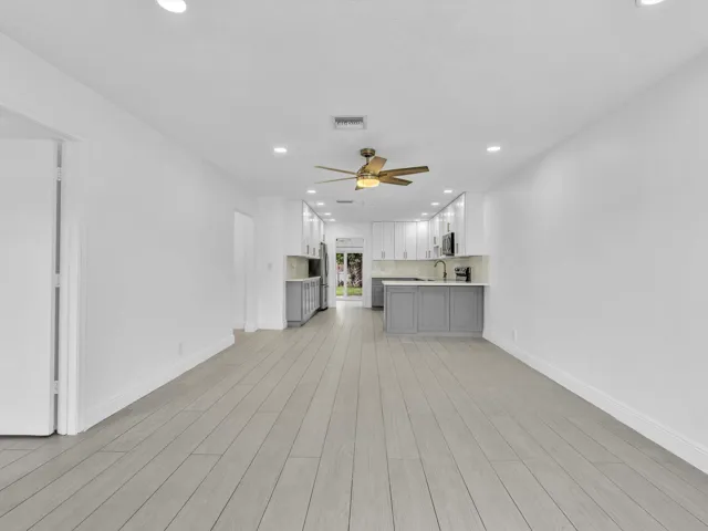 Open-concept layout with light wood-finish vinyl flooring, recessed lighting, and a ceiling fan
