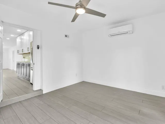Bedroom with wood-finish ceiling fan with integrated lighting, and light grey vinyl flooring.