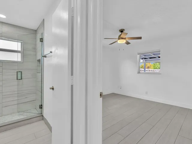 View of bedroom and 2nd bathroom with glass-enclosed shower with horizontal tile surround and a built-in niche