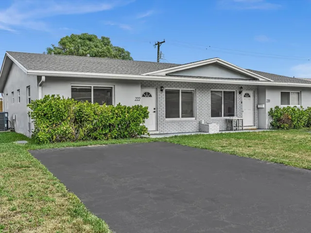 Grey exterior with white brick facade, asphalt driveway, and mature landscaping