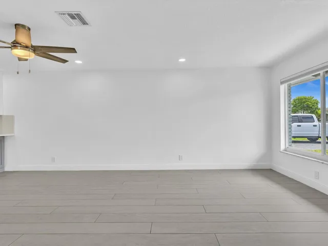 Spacious room featuring wood-finish vinyl flooring, recessed lighting, and a ceiling fan