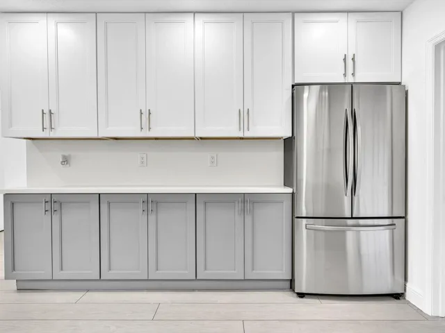 Kitchen featuring wood-finish vinyl flooring, two-tone cabinetry with white upper and grey lower units, stainless steel appliances, recessed lighting, and a white countertop