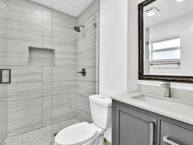 Primary Bedroom glass-enclosed shower with a recessed niche, hexagonal tile flooring, and horizontal tile walls