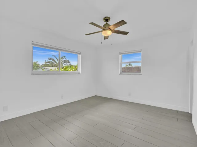 Bedroom with wood-finish ceiling fan with integrated lighting, and light grey vinyl flooring