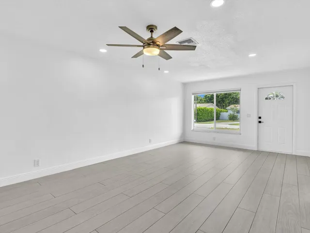 Spacious room featuring wood-finish vinyl flooring, recessed lighting, and a ceiling fan