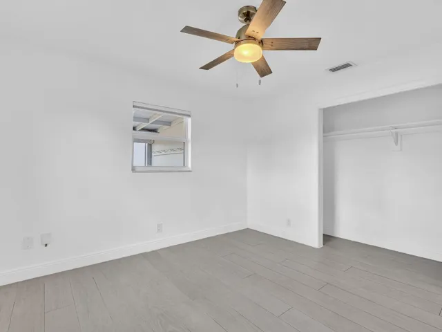 Bedroom with wood-finish ceiling fan with integrated lighting, and light grey vinyl flooring