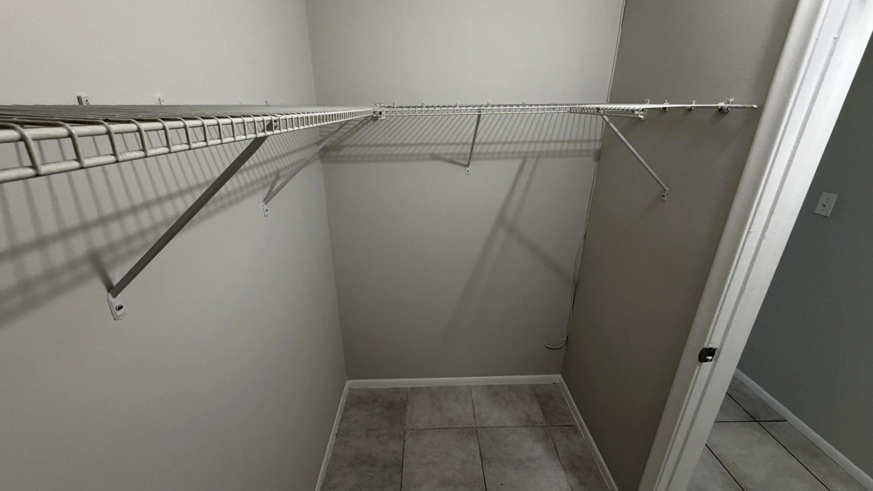 Integrated wire shelving system, neutral wall paint, and tiled flooring