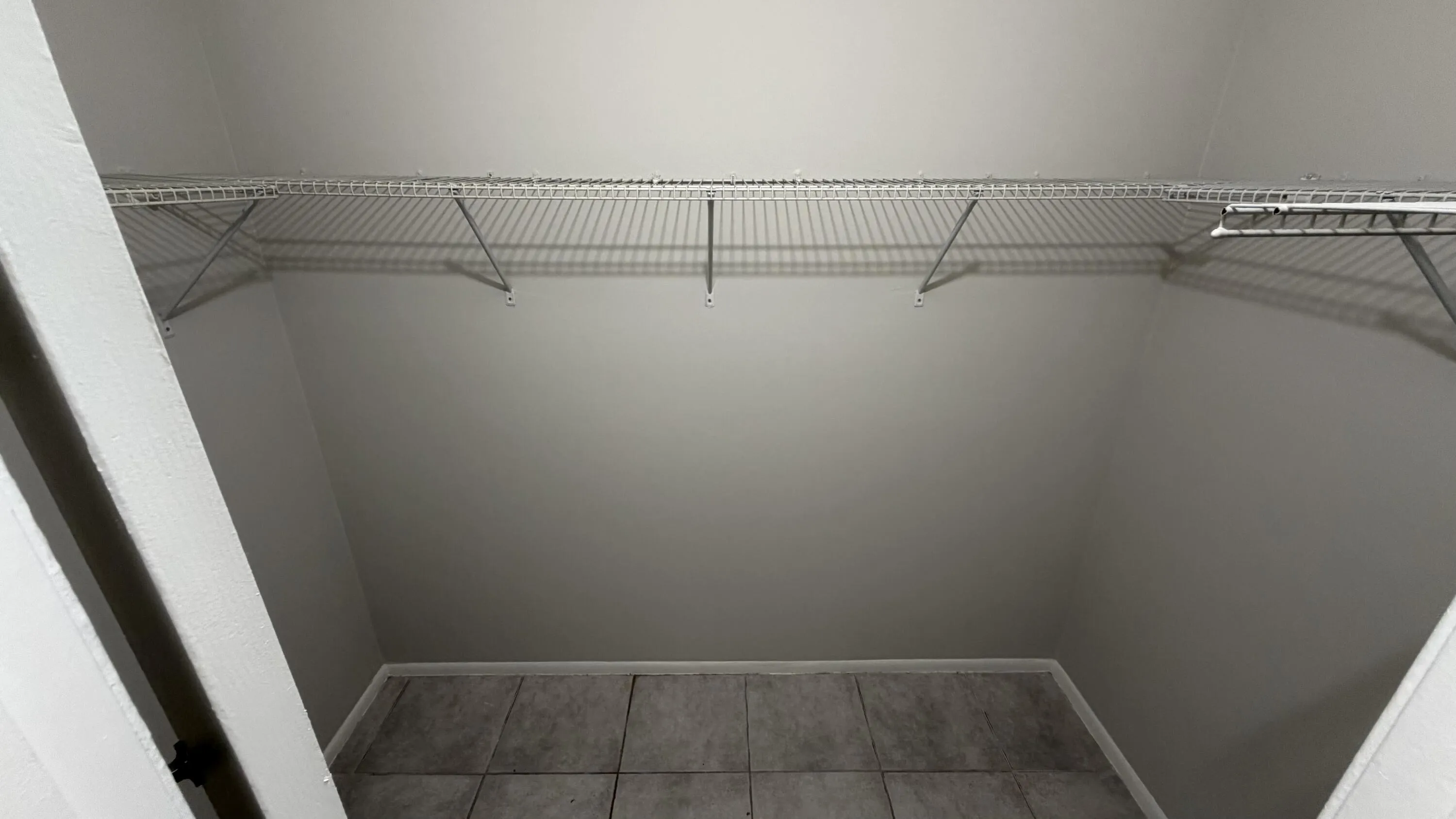 Tiled flooring with a wire shelving system and light-toned wall paint