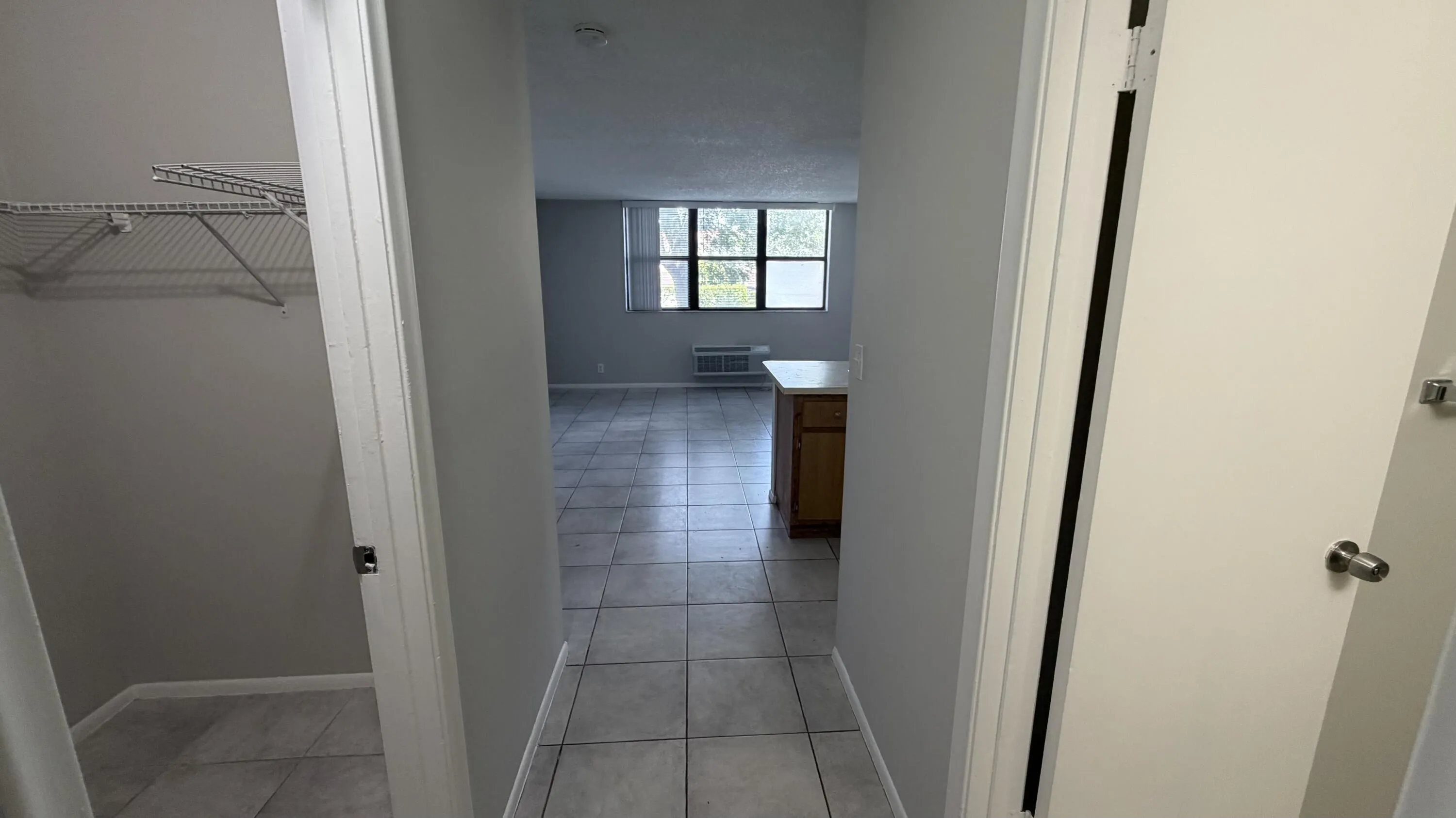 Hallway featuring tile flooring, neutral wall tones, and a built-in wire shelving unit
