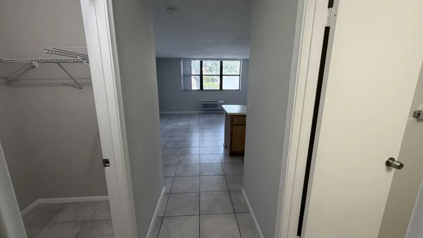 Hallway featuring tile flooring, neutral wall tones, and a built-in wire shelving unit