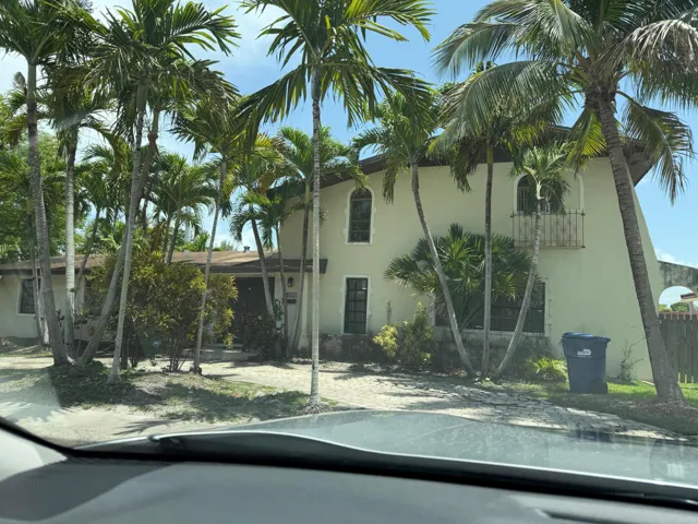 Stucco exterior with arched windows, wrought iron balcony, and mature palm trees