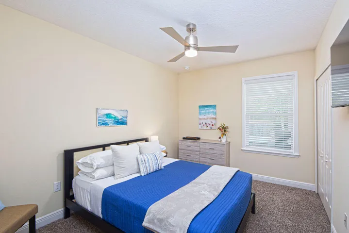 Bedroom with queen bed, ceiling fan, carpet and window with blinds