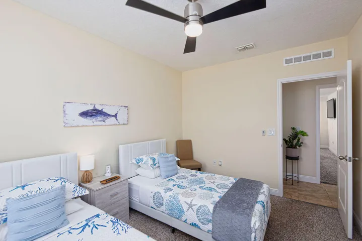 Guest bedroom with two beds, ceiling fan and carpet, ideal for families or groups
