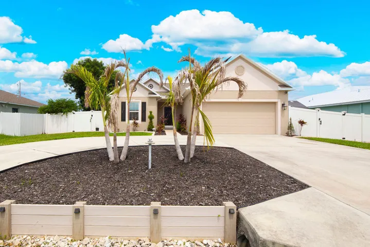 Contemporary single-story residence with an attached garage, featuring a concrete driveway and a white privacy fence