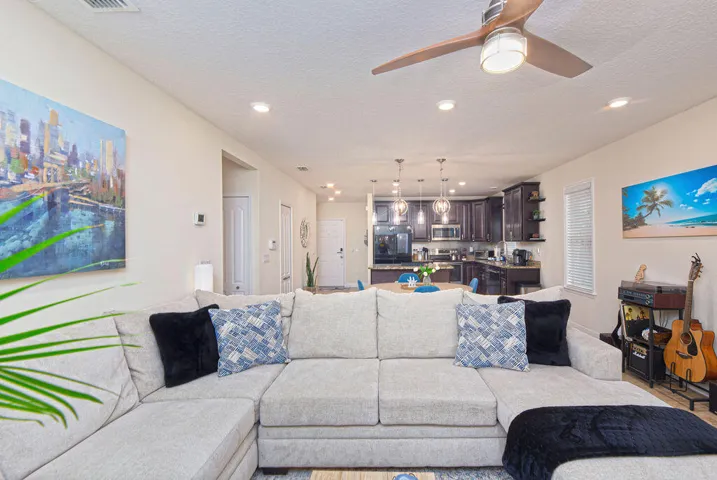 Recessed lighting throughout, a ceiling fan with integrated lighting, dark wood-finish kitchen cabinetry, and pendant light fixtures