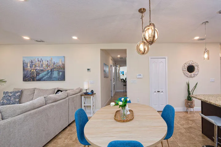 Recessed ceiling lighting, decorative pendant fixtures, tiled flooring, wood-finish dining table, and granite countertop