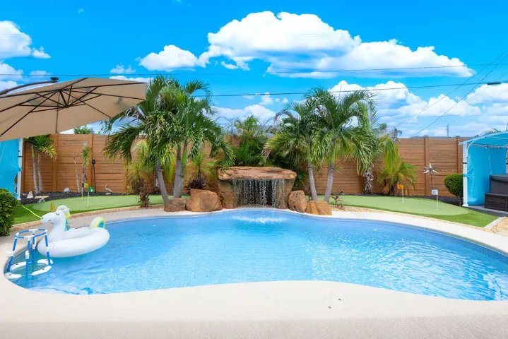 Heated pool with waterfall, hot tub, gazebo and turf yard