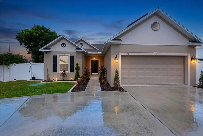 Stucco exterior with a two-car garage, concrete driveway, and covered entry
